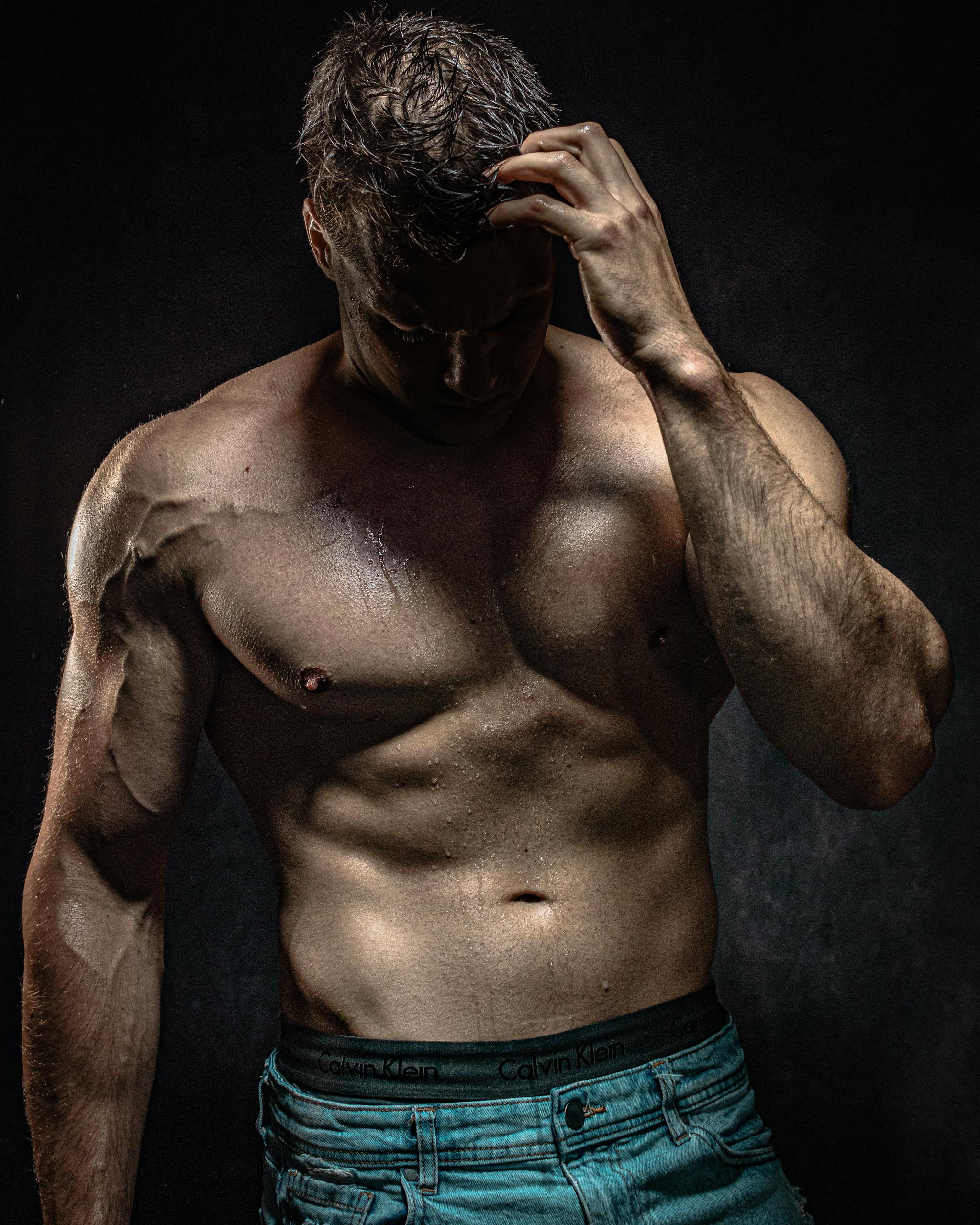 A man with his shirt off and his hands on his head